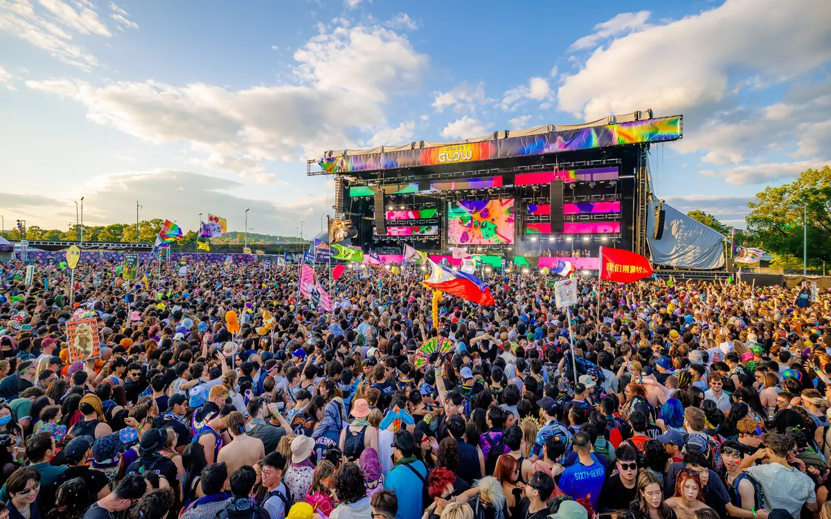 A wide daytime view of the Project GLOW festival crowd and stage